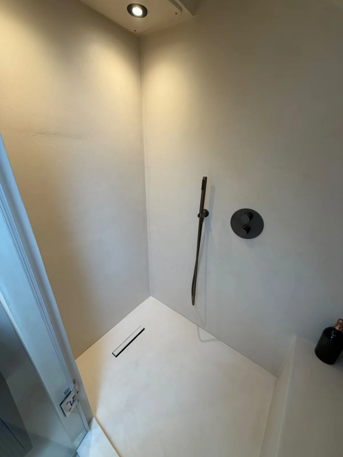 White microcement shower room with a seamless floor and linear drain