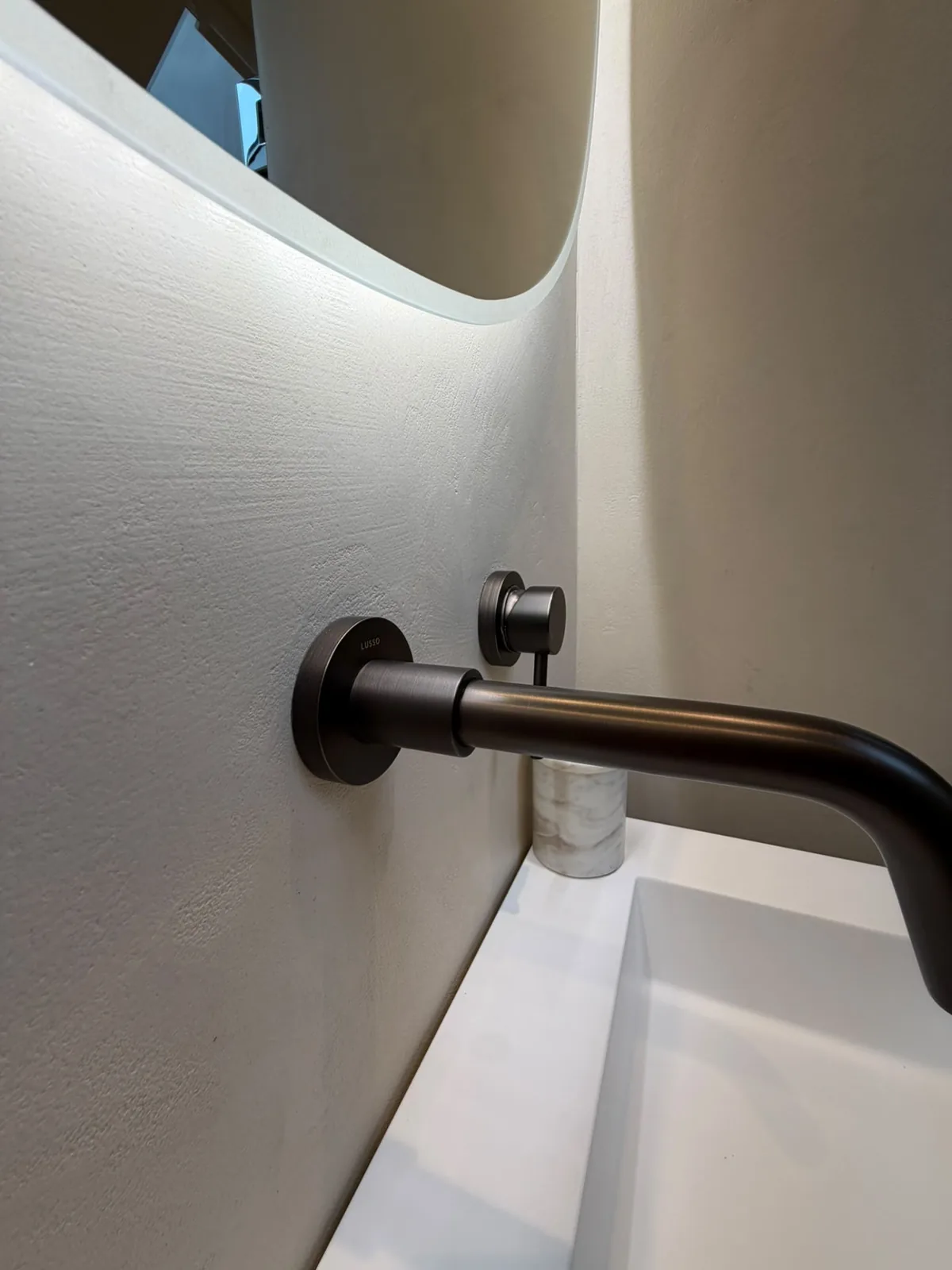 Brass basin tap against a hand-finished microcement bathroom wall