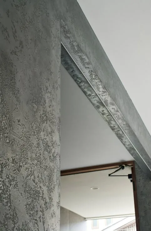 Liquid metal wall finish wrapped seamlessly around a doorway reveal