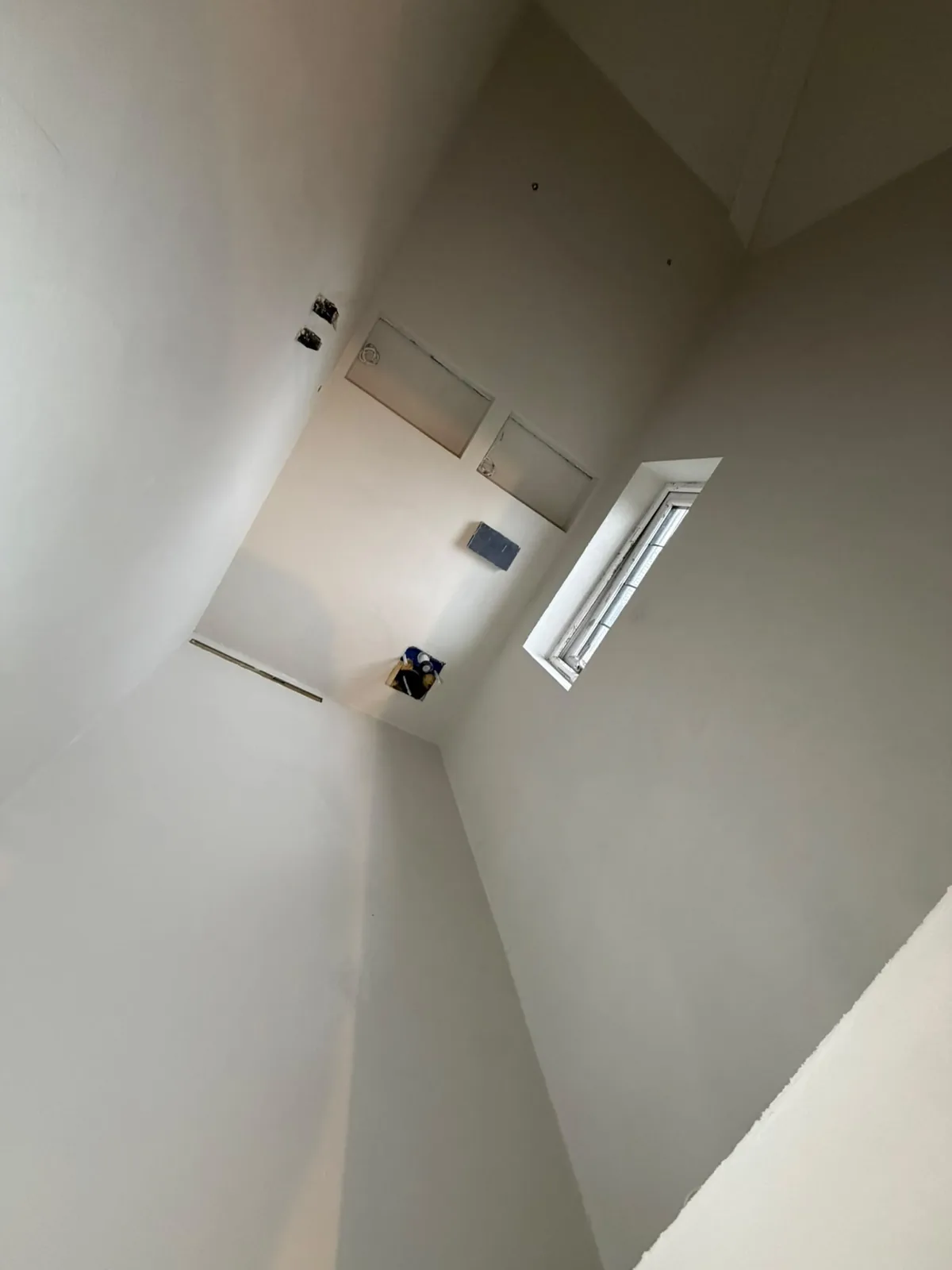 White microcement walls and floor in a bright room with tall windows