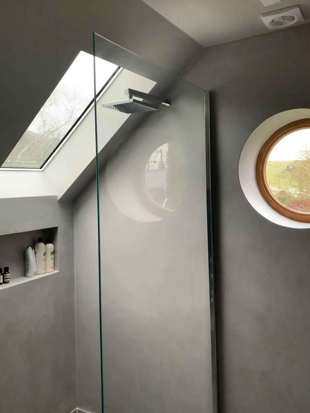 Grey microcement bathroom walls and floor beneath a roof skylight