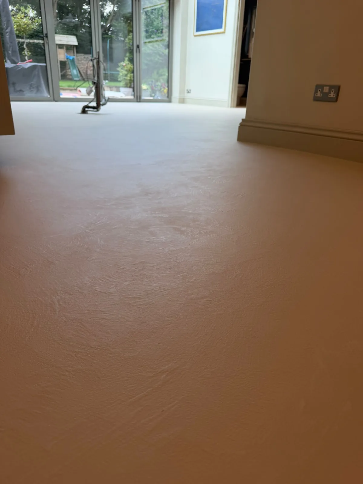 Seamless microcement living room floor beside bifold doors