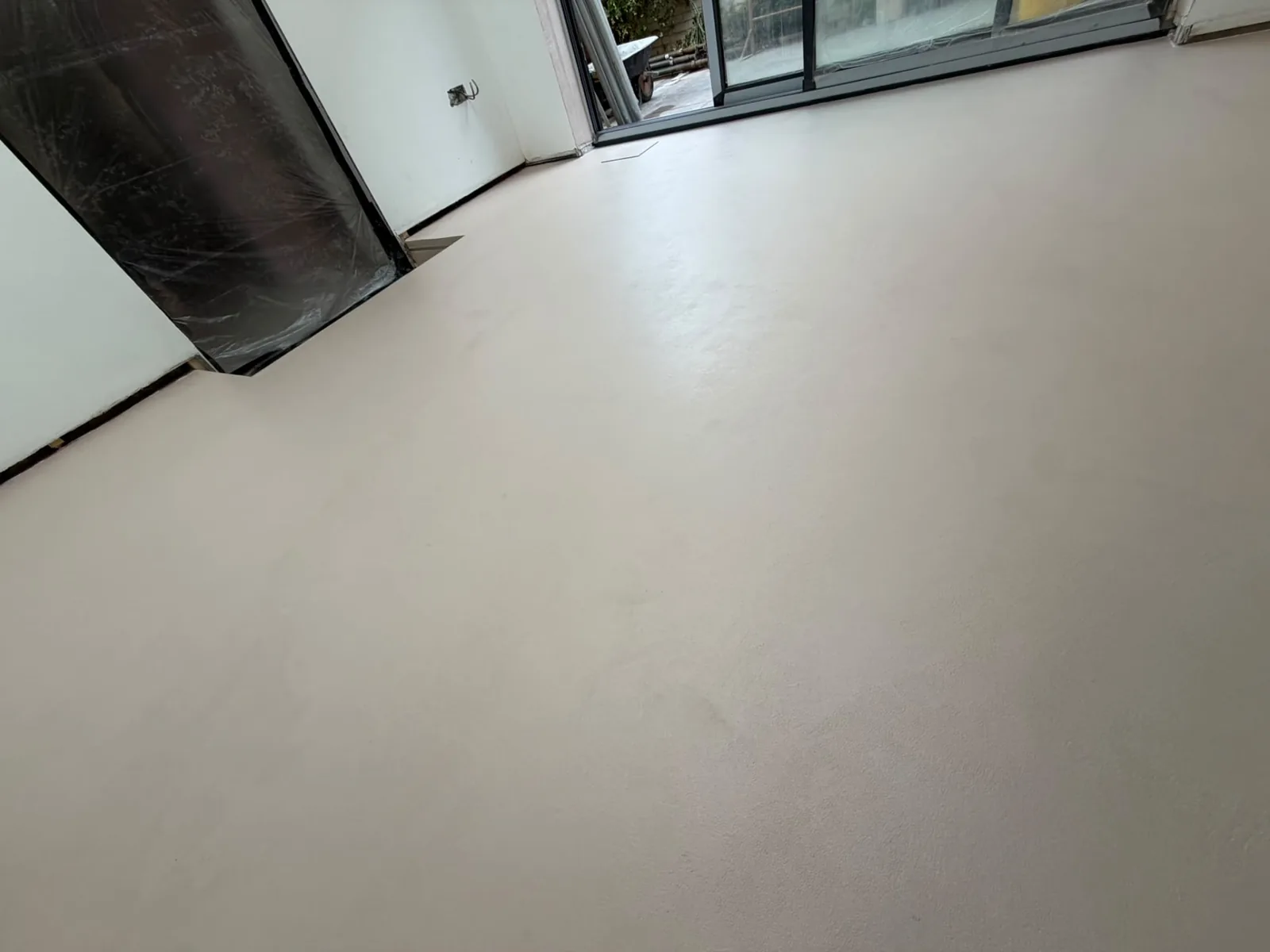 Large cream microcement floor beside sliding patio doors