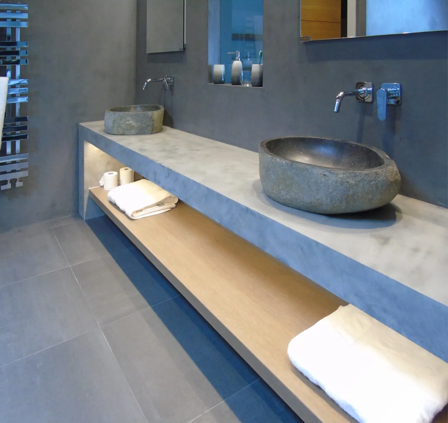 Polished microcement bathroom worktop with stone basins and a seamless microcement wall
