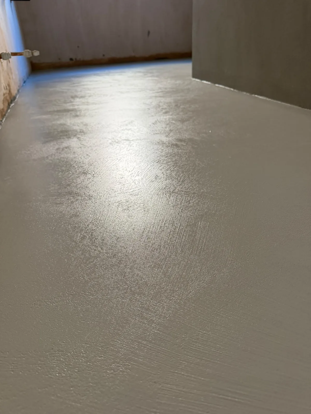 Polished seamless microcement floor with a soft sheen running through a hallway
