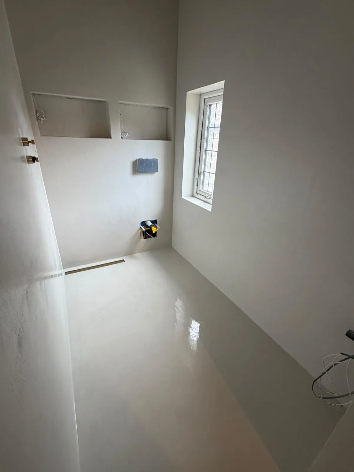 Microcement wet room with a linear drain and continuous walls and floor