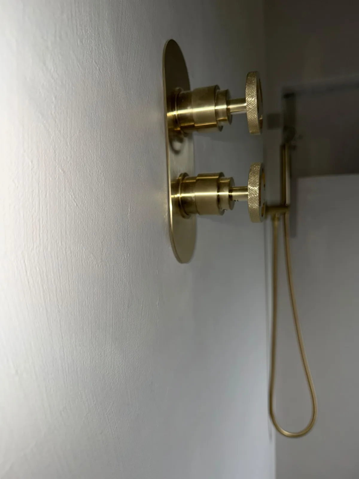 Brass shower controls set into a seamless microcement shower wall