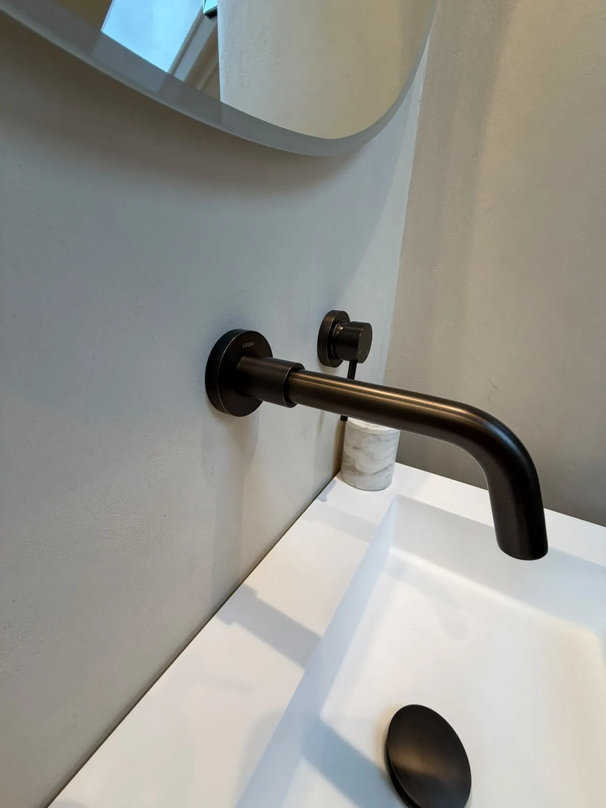 Brass mixer tap on a microcement bathroom wall finished in Solidro