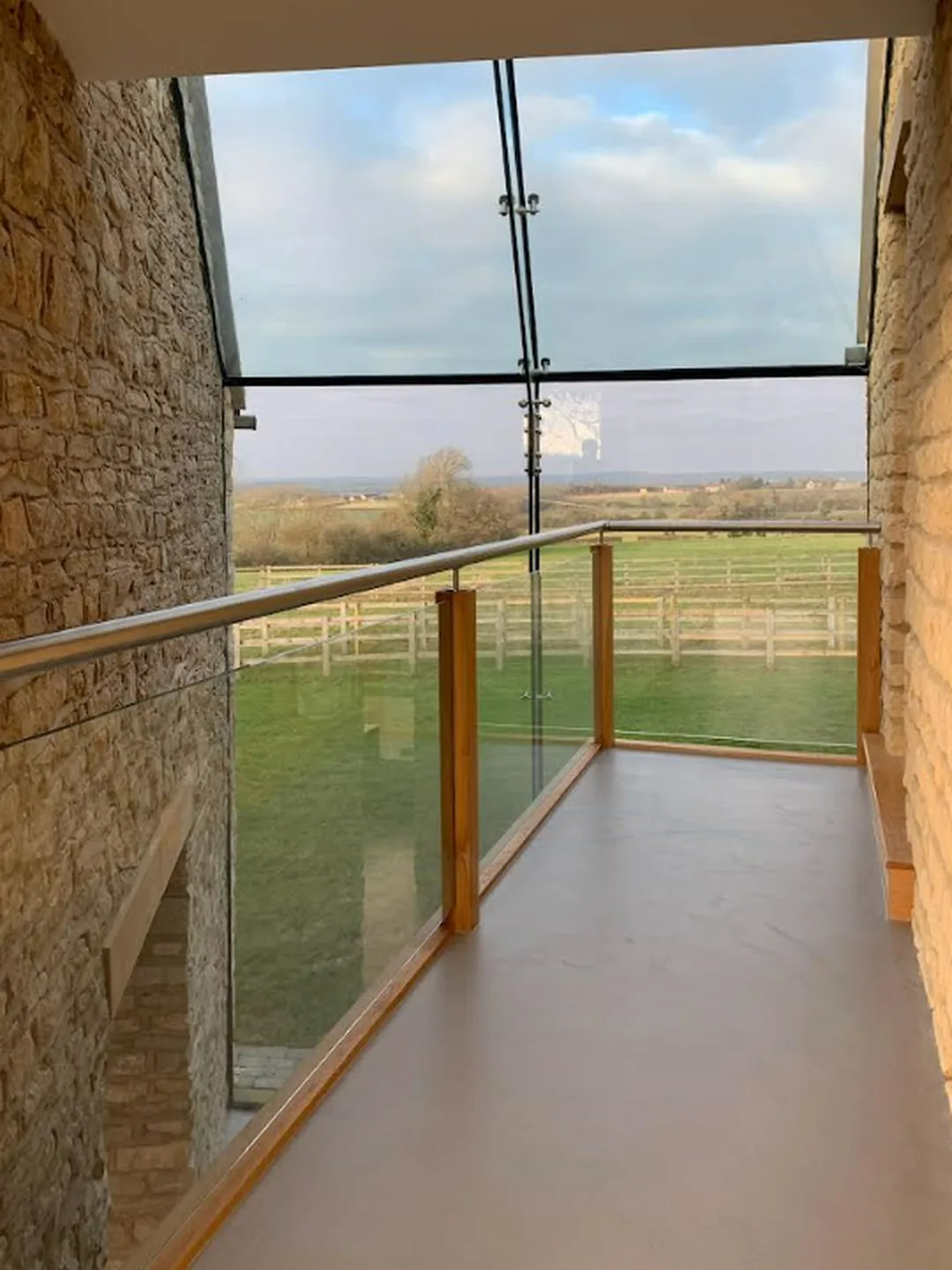 Microcement landing floor on a glazed barn conversion walkway