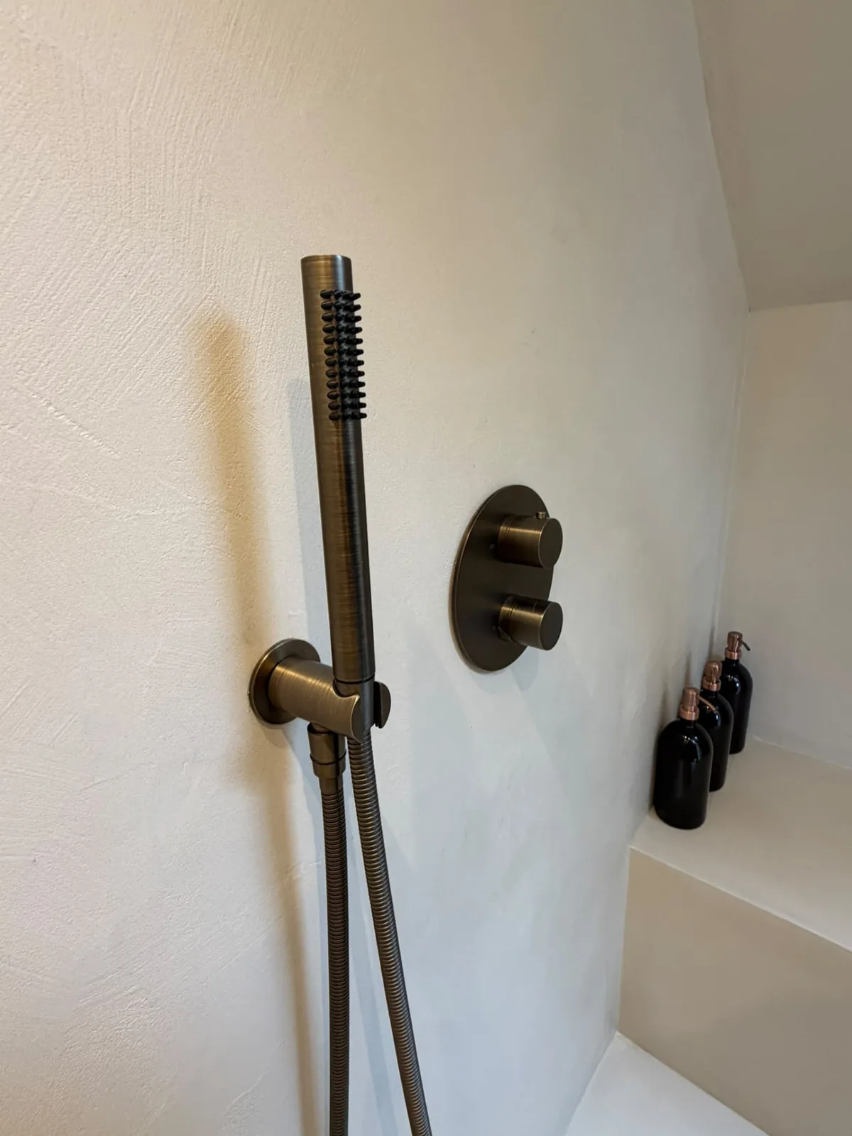 Brass shower handset on a seamless microcement shower wall