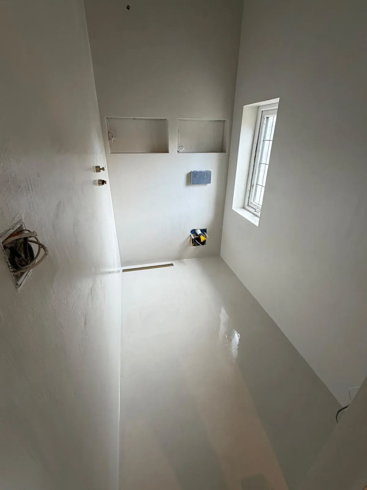 White microcement bathroom with seamless floor, walls and recessed niches