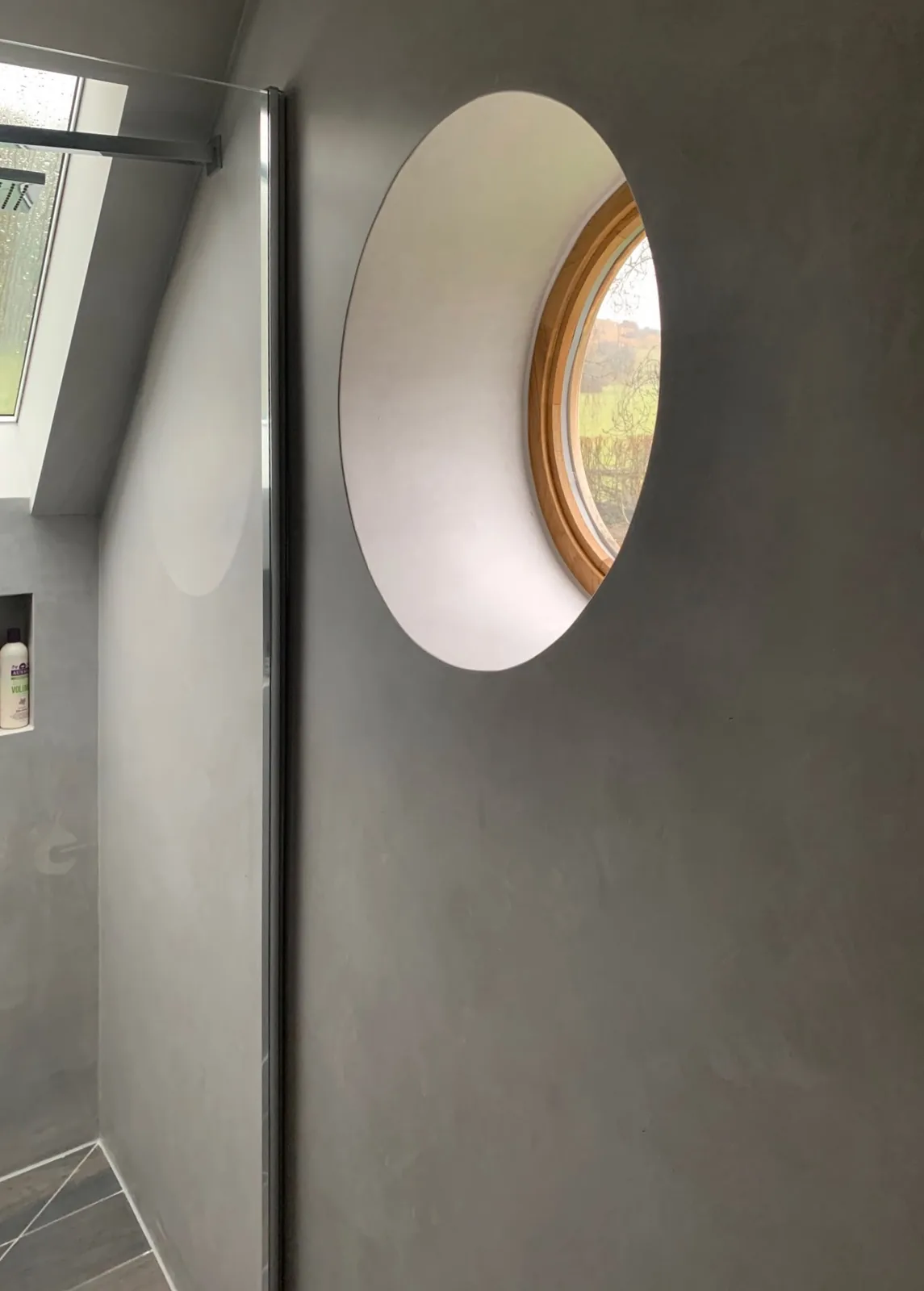 Grey microcement bathroom wall around a circular window