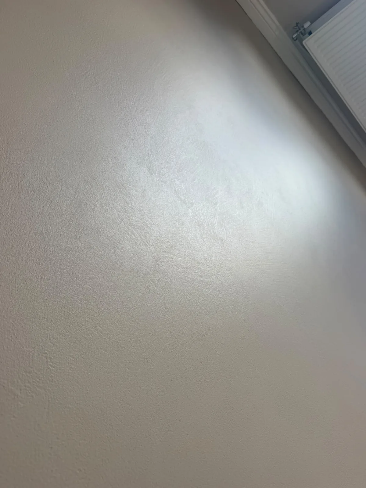 Close-up of a white microcement wall finish showing fine texture