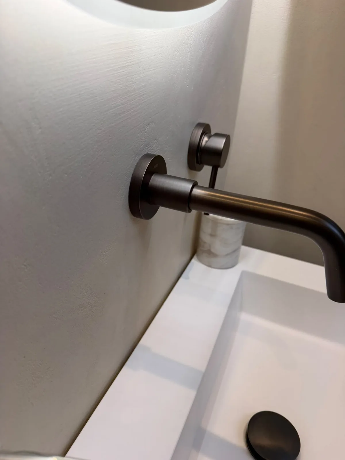 Brass tap set against a seamless microcement bathroom wall