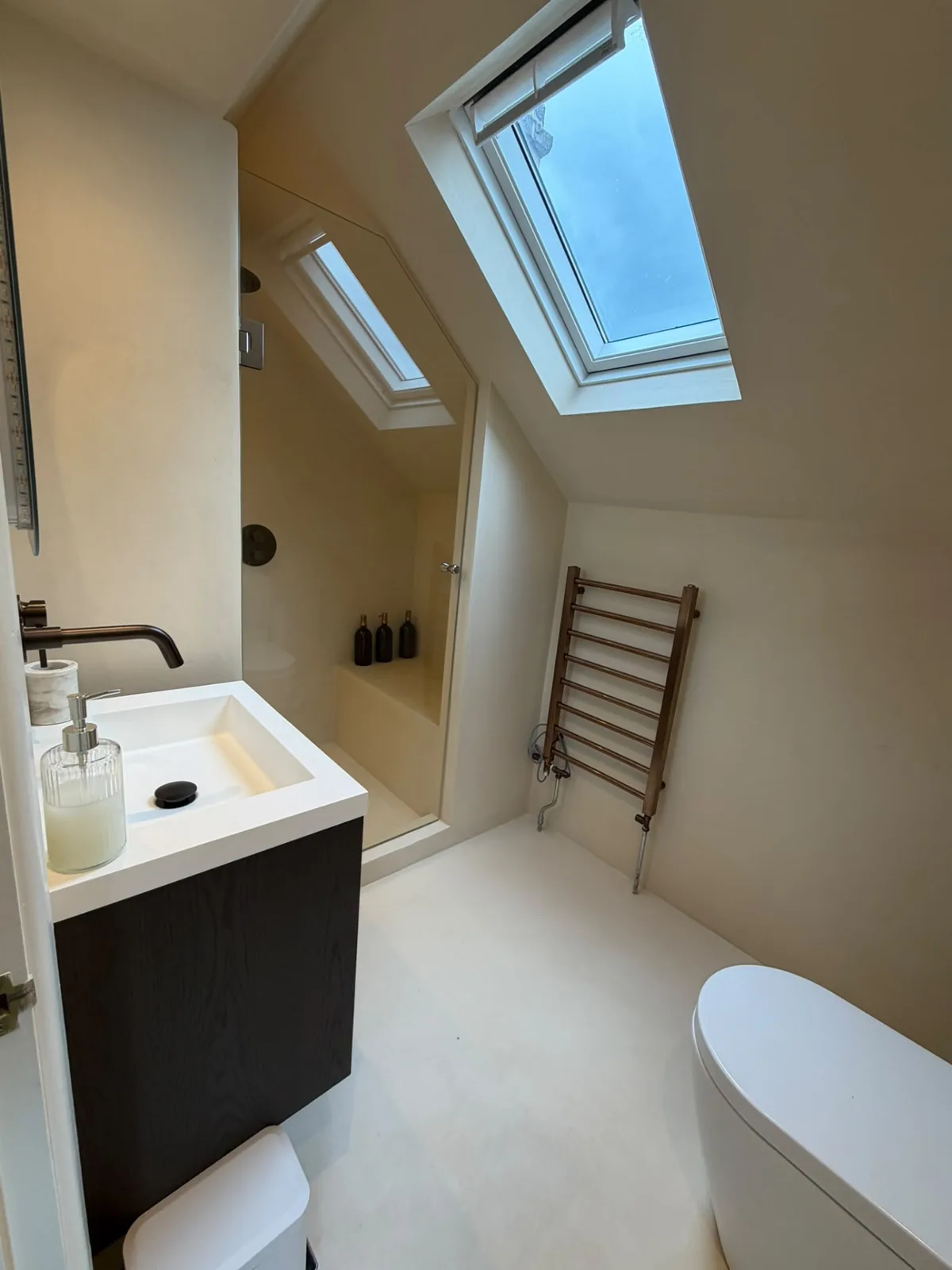 Microcement loft bathroom lit by a roof skylight