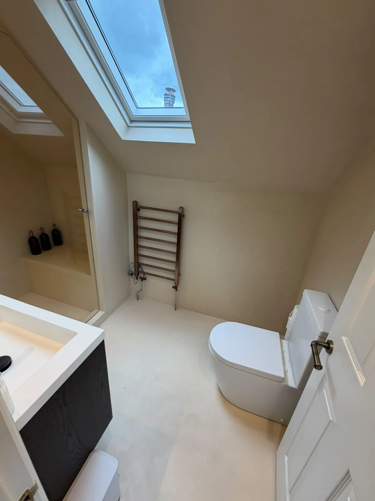 Microcement bathroom beneath a skylight with seamless walls and floor