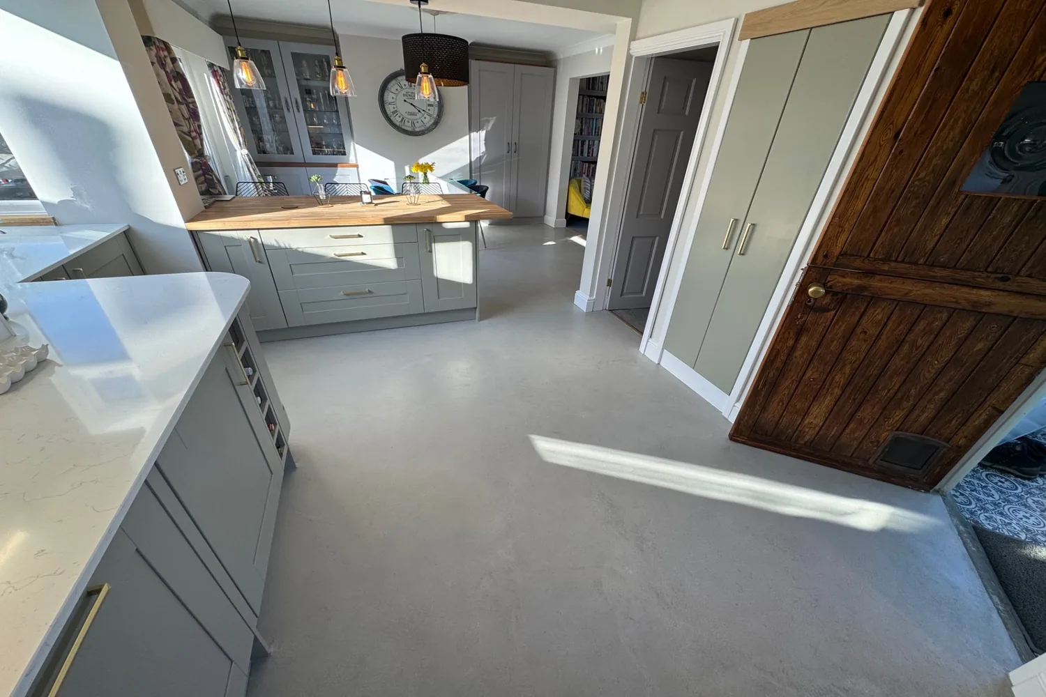 Grey microcement kitchen floor running seamlessly through to a hallway