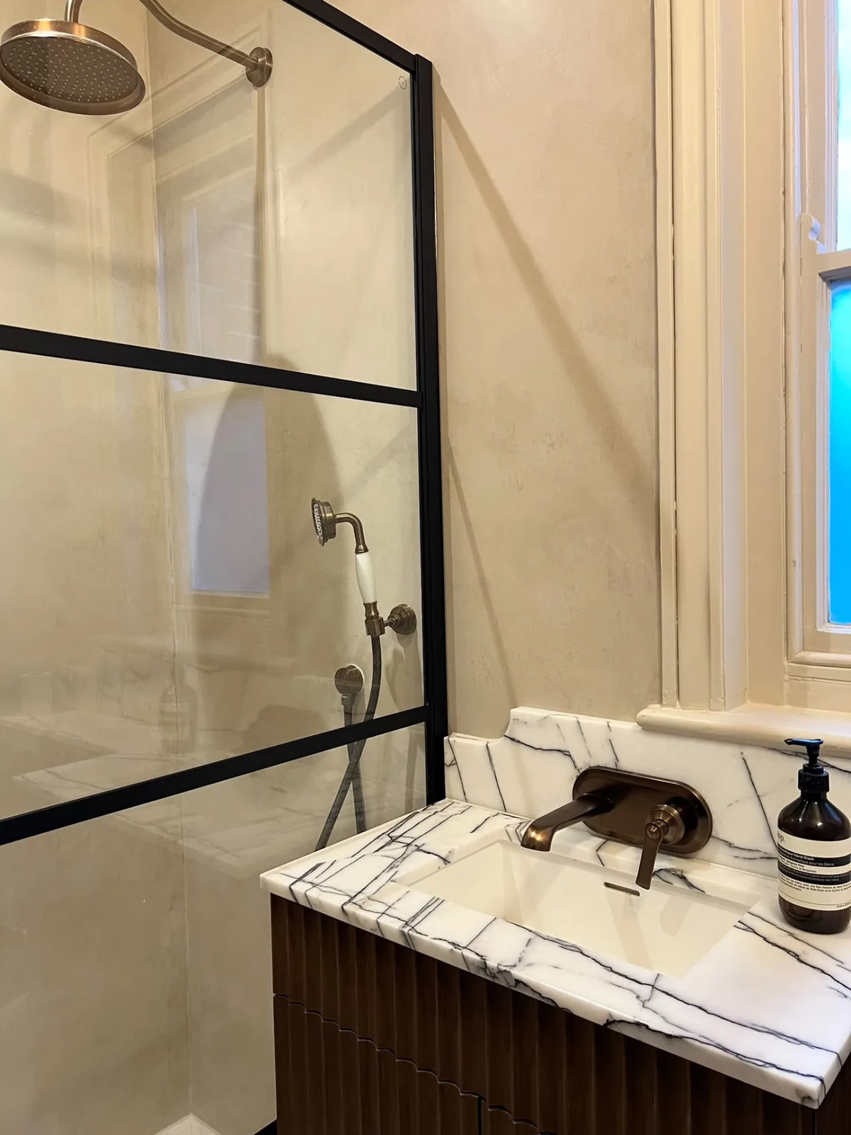 Beige microcement shower enclosure and vanity in a seamless bathroom