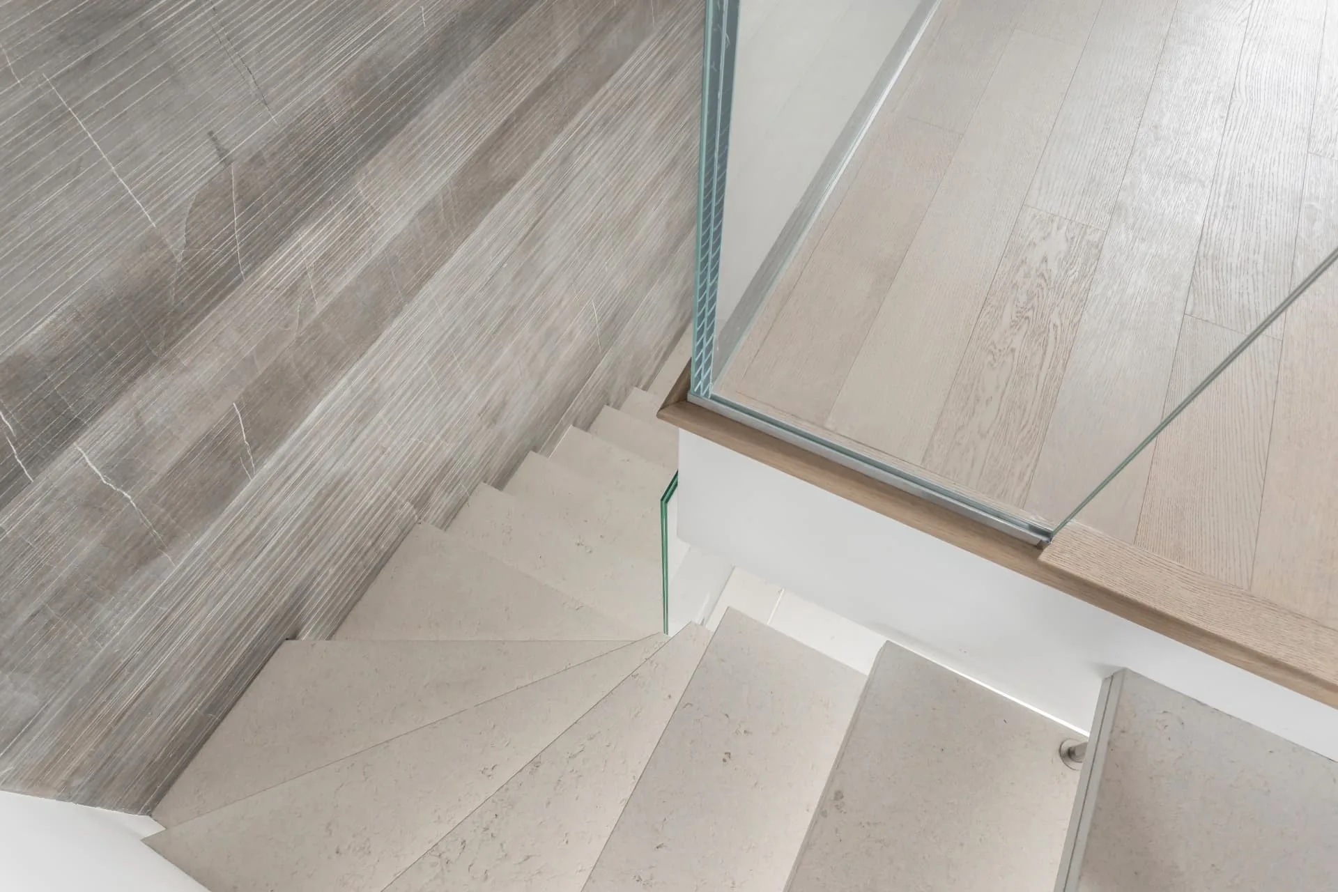 Seamless microcement staircase with pale stone-toned treads and a glass balustrade