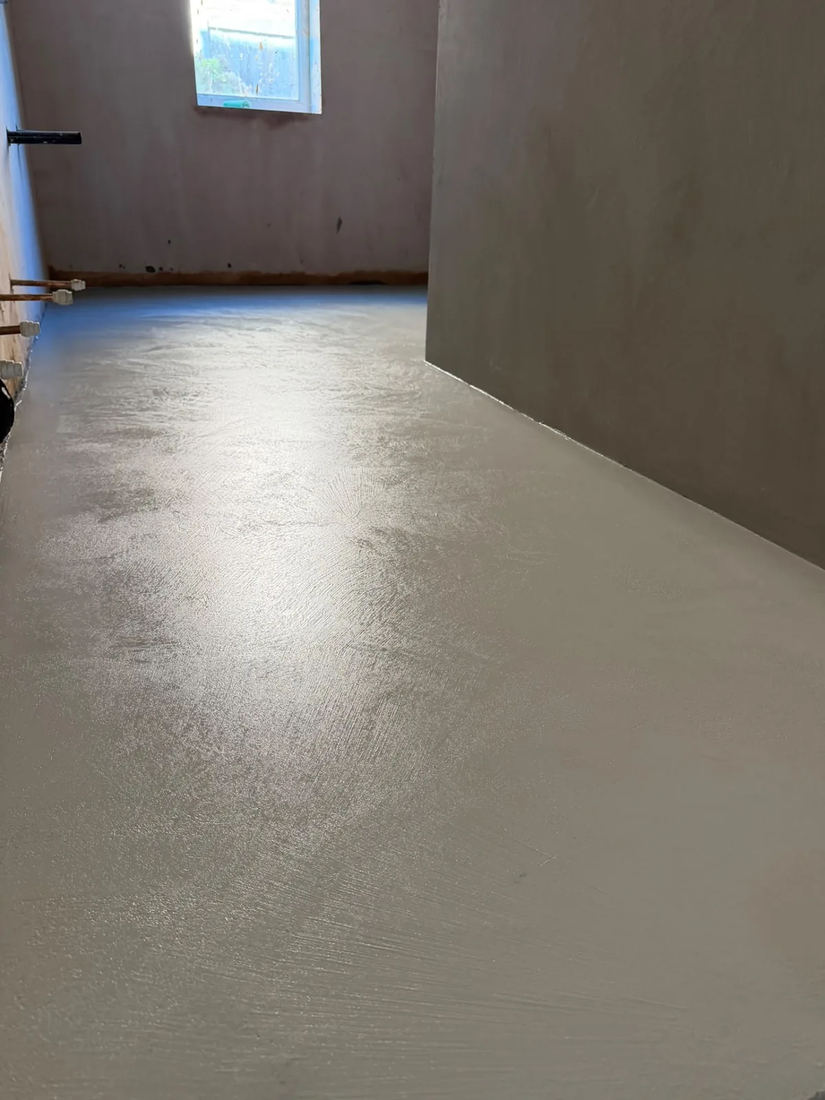 Microcement hallway floor reflecting daylight along its full length