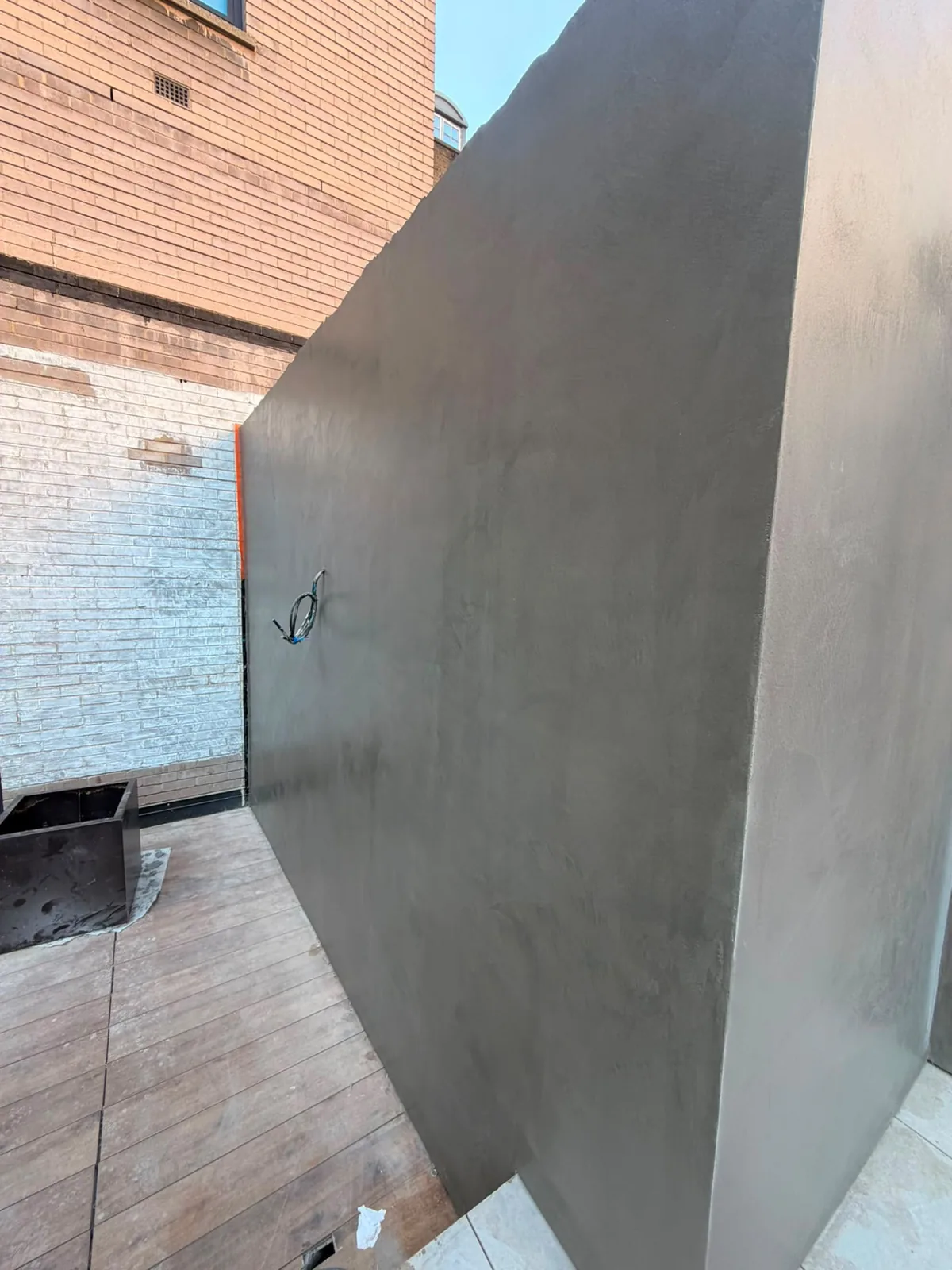 Dark microcement courtyard wall with a smooth continuous finish