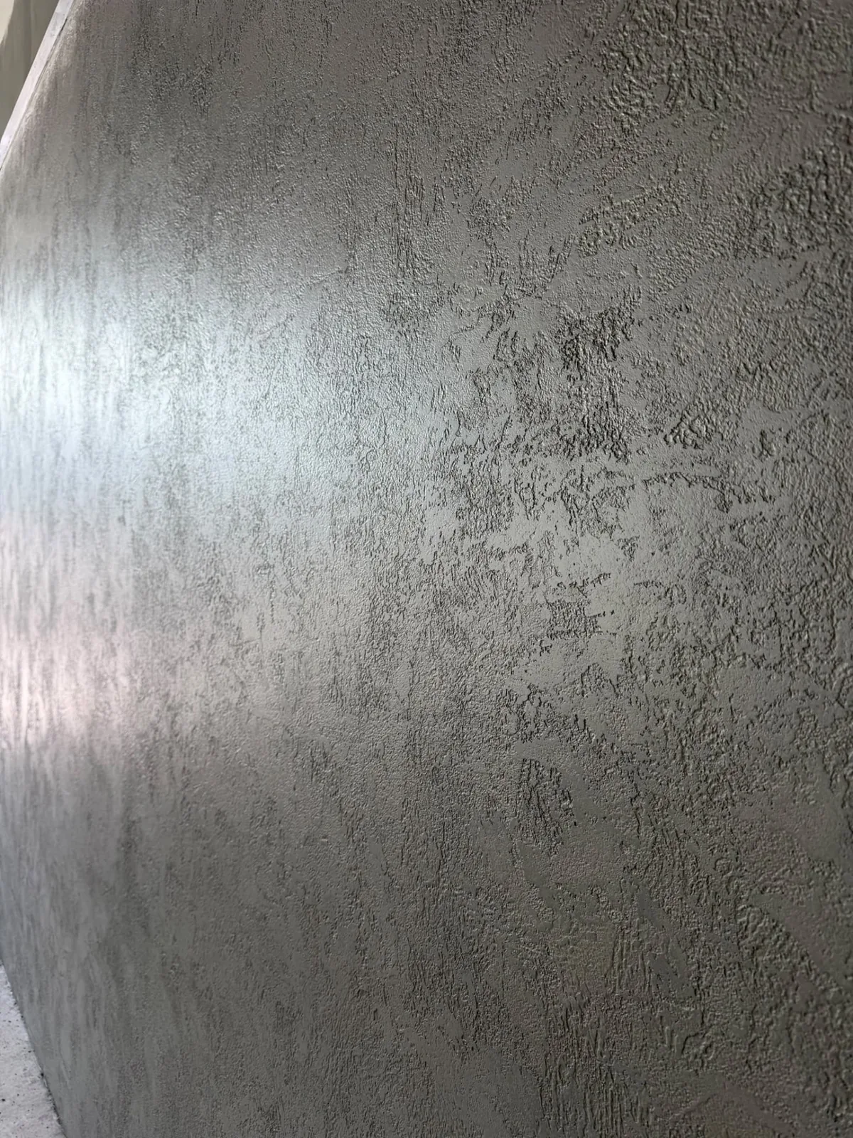 Textured grey microcement wall finish showing hand-worked movement