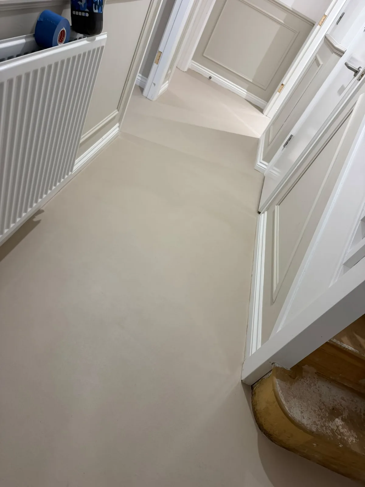 Microcement hallway floor finished around a radiator and skirting